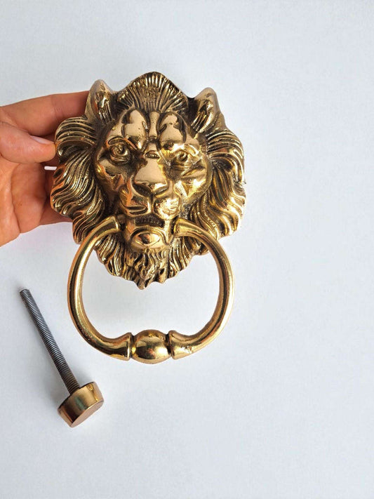 Gold lion-shaped door knocker with installation screw on a white background