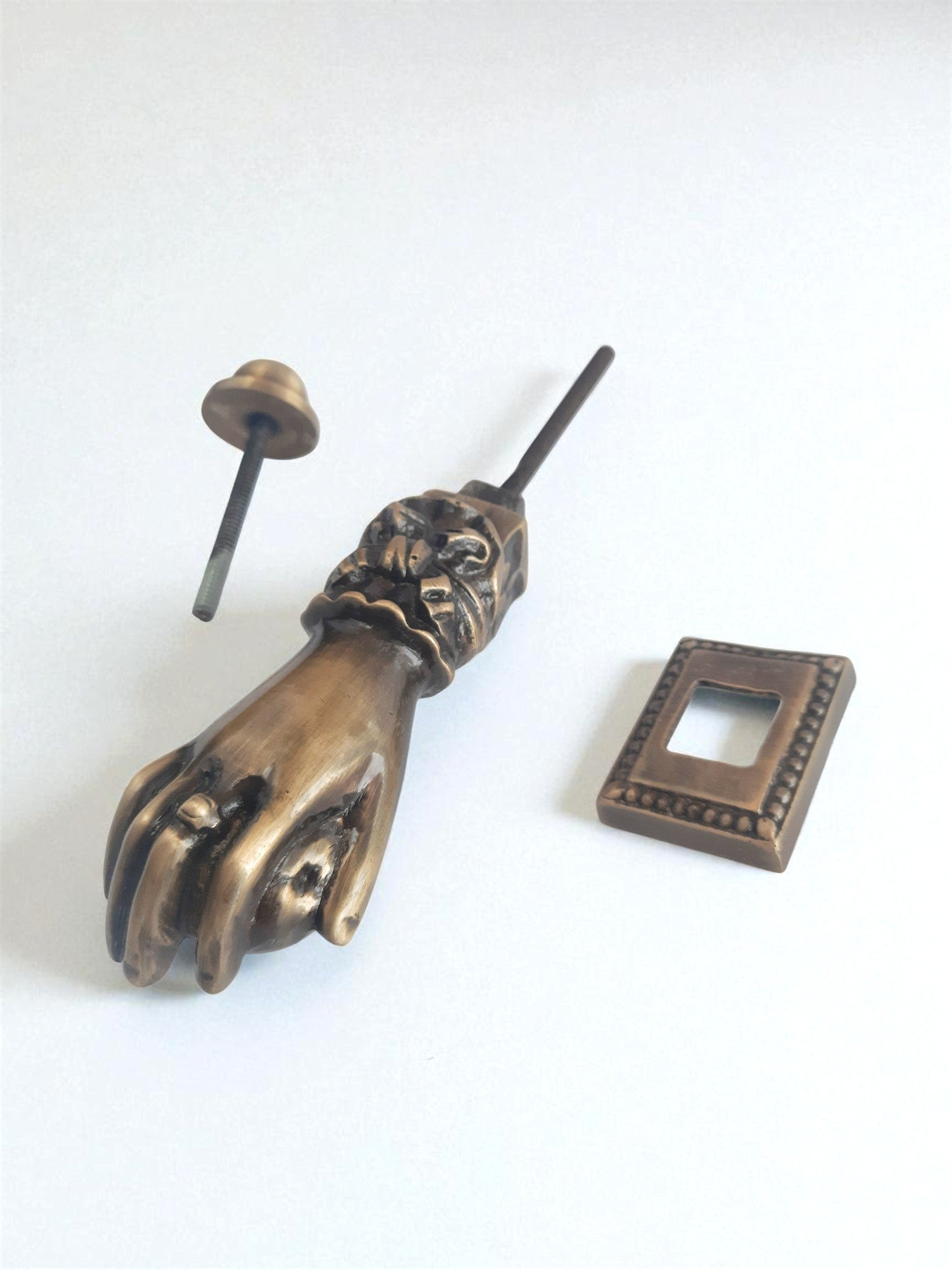 Bronze hand-shaped door knocker on a white background
