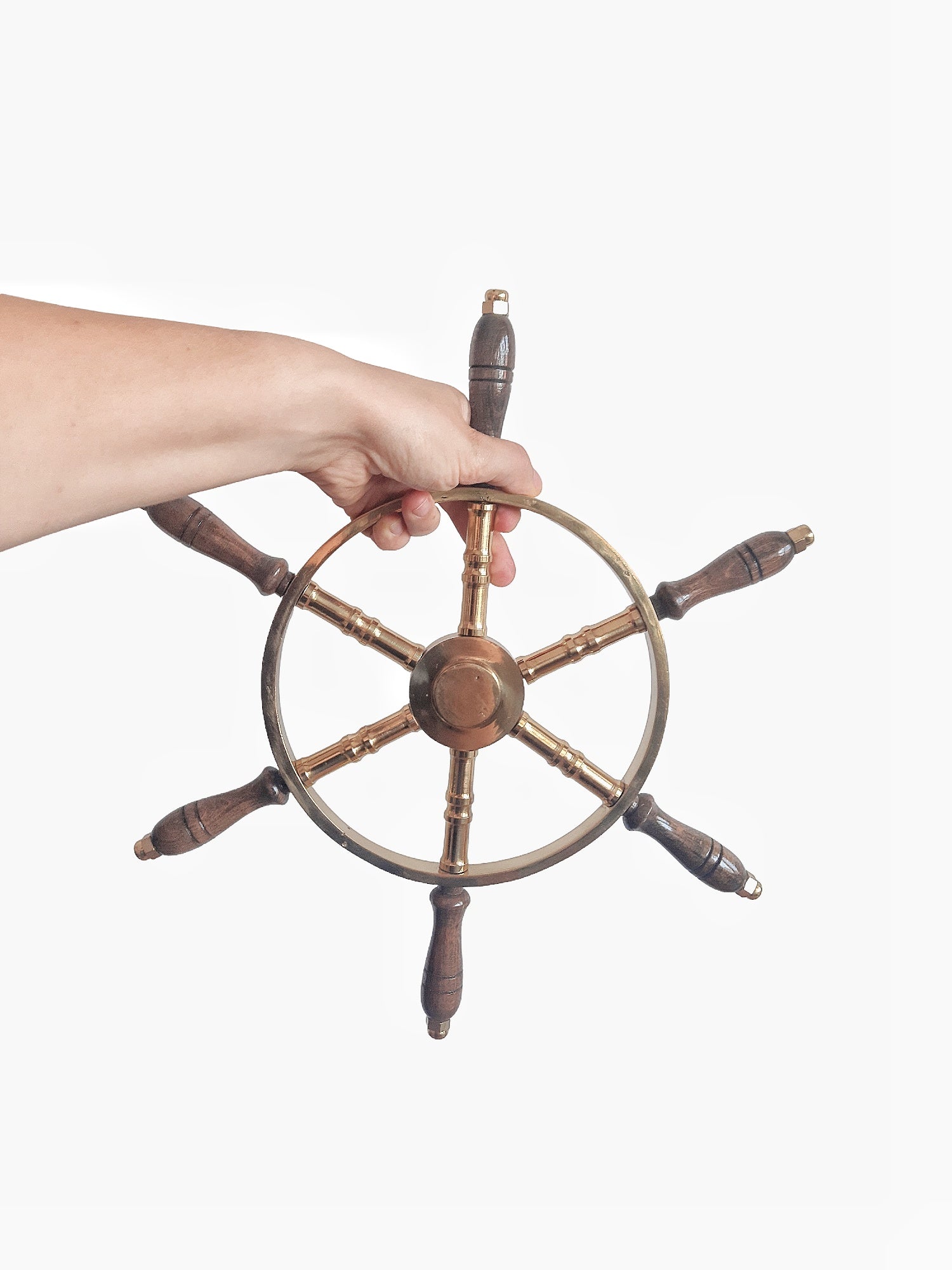 Hand holding a wooden ship's steering wheel on a white background