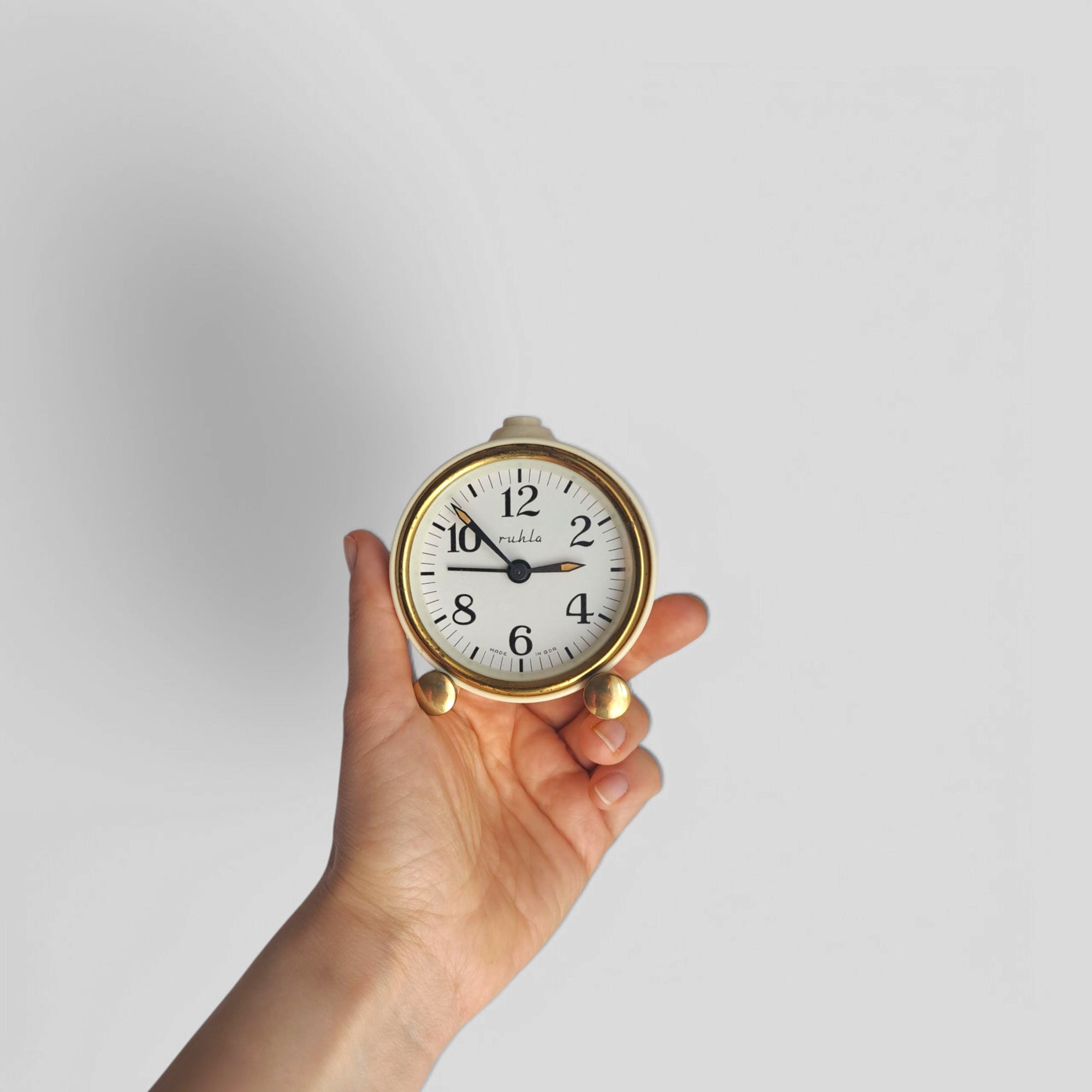 Hand holding retro beige Ruhla alarm clock