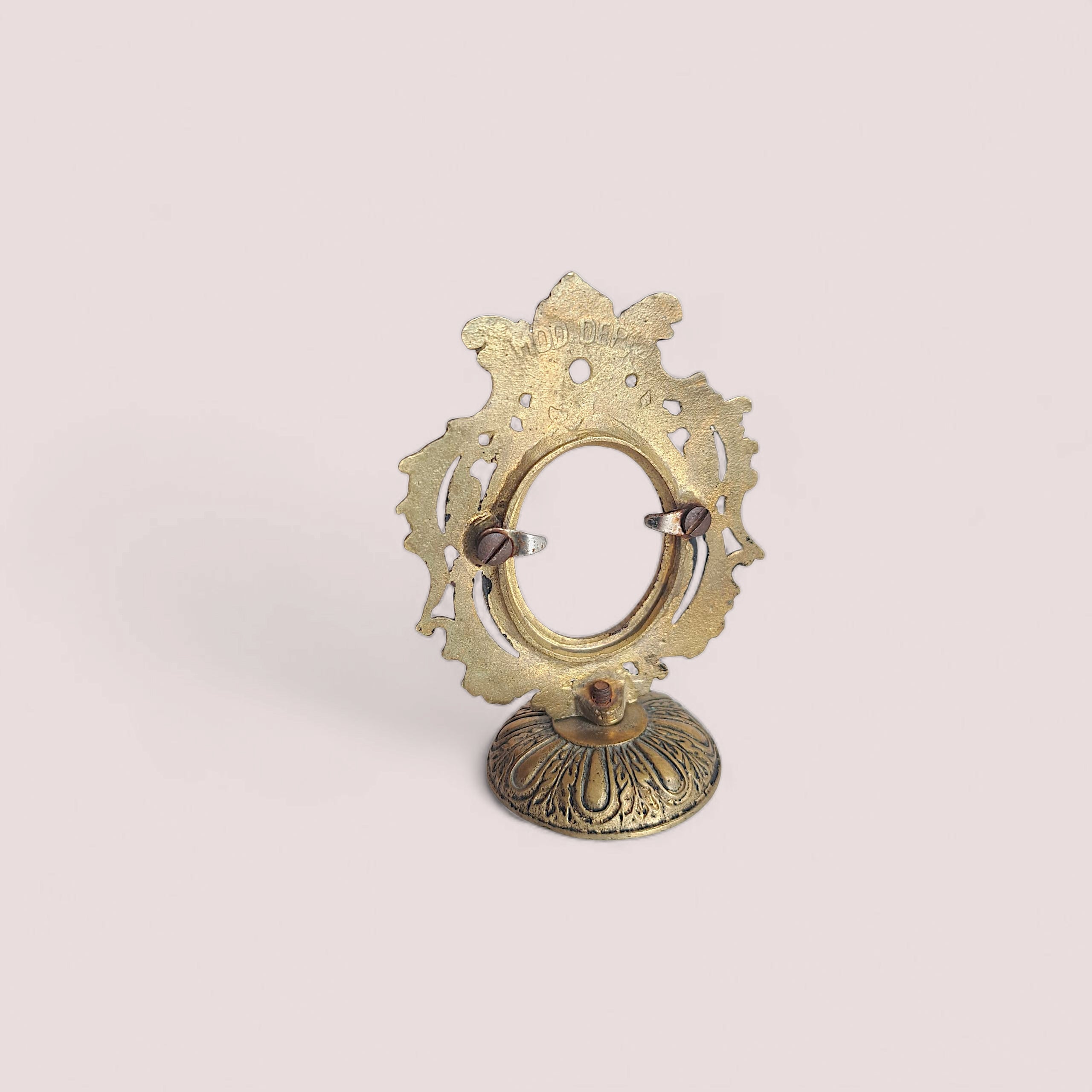 Decorative brass object on a light pink background