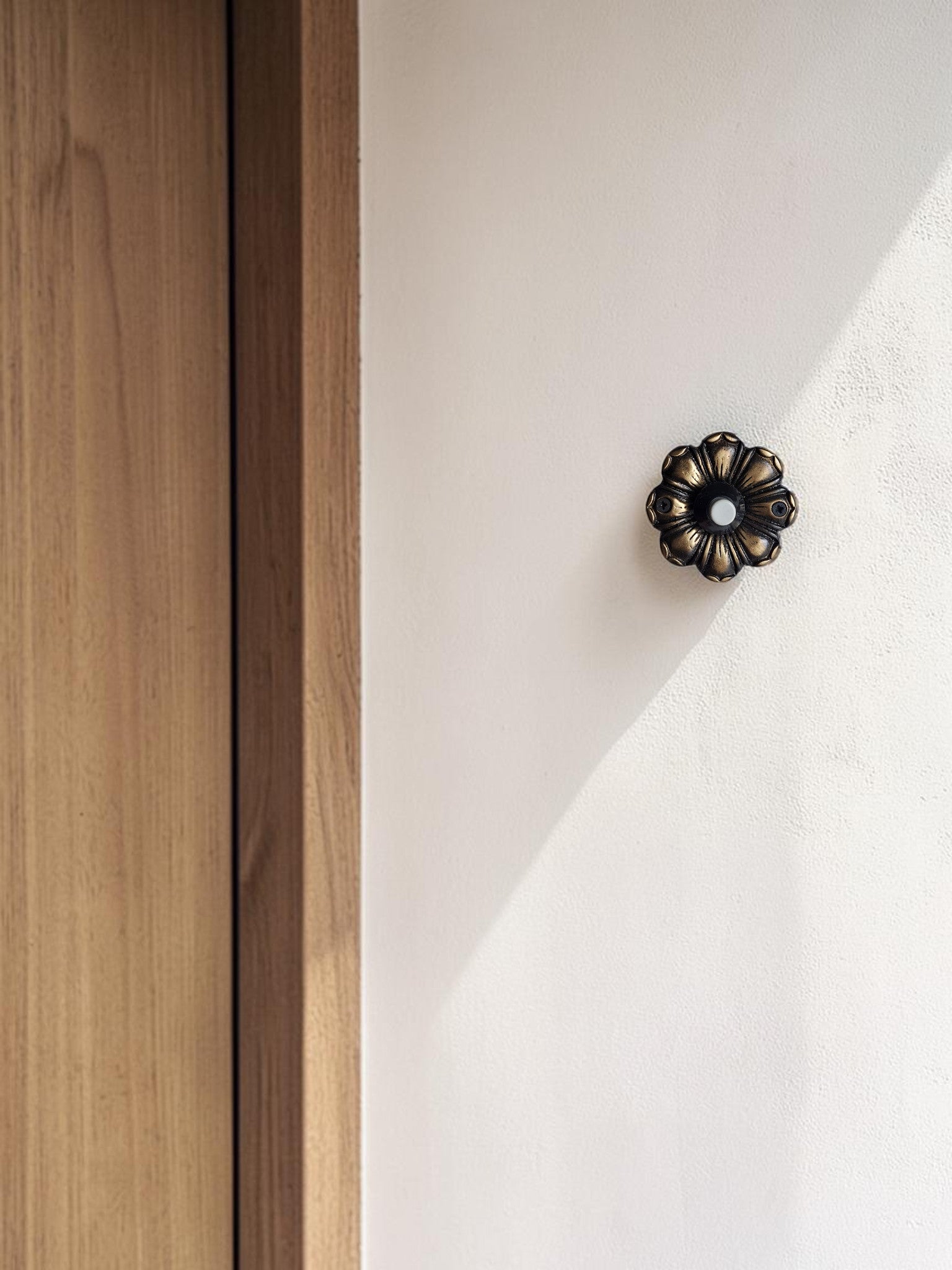 Decorative brass entry doorbell on textured exterior wall