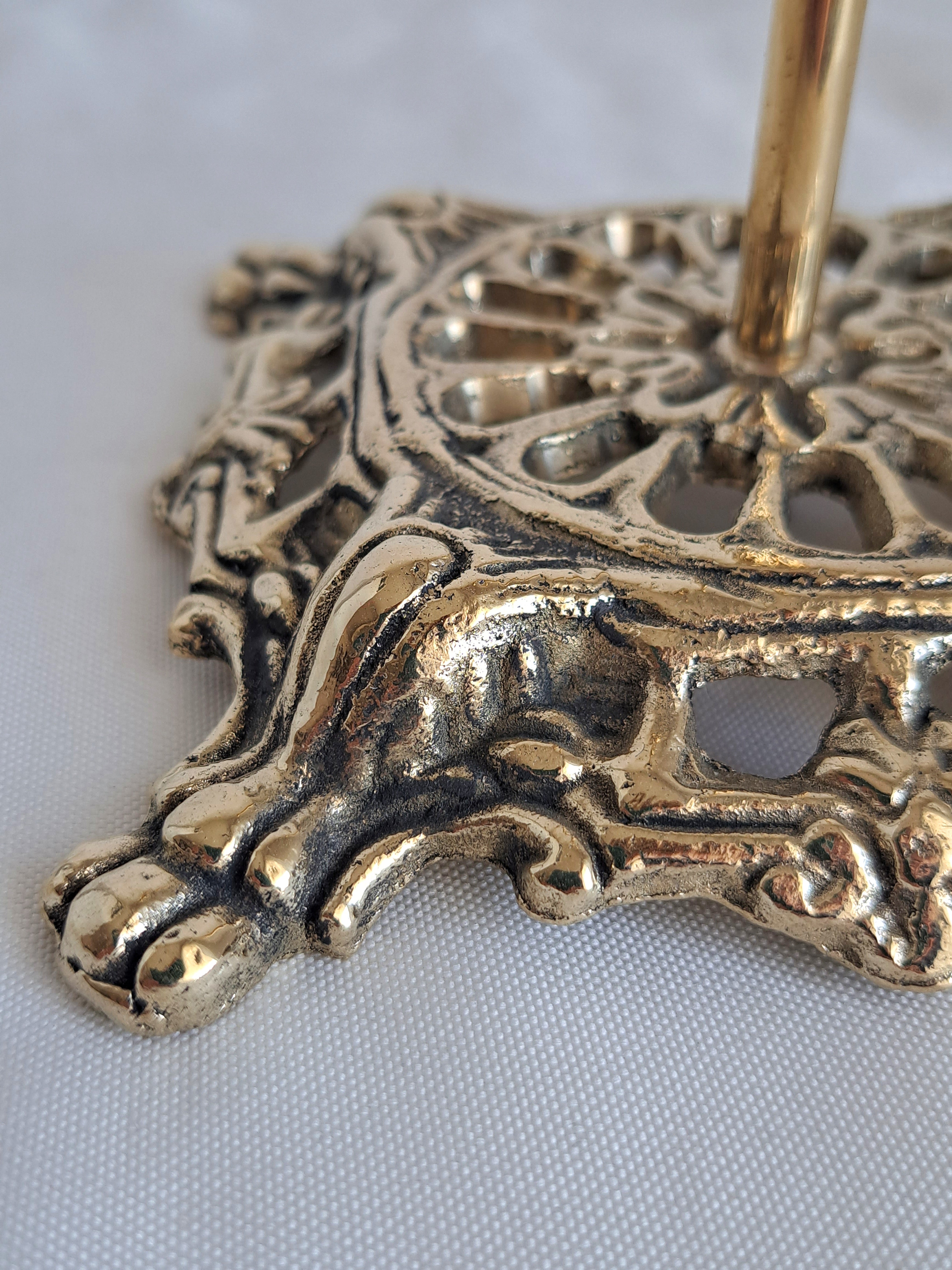 Decorative gold metal stand with intricate patterns on a white background
