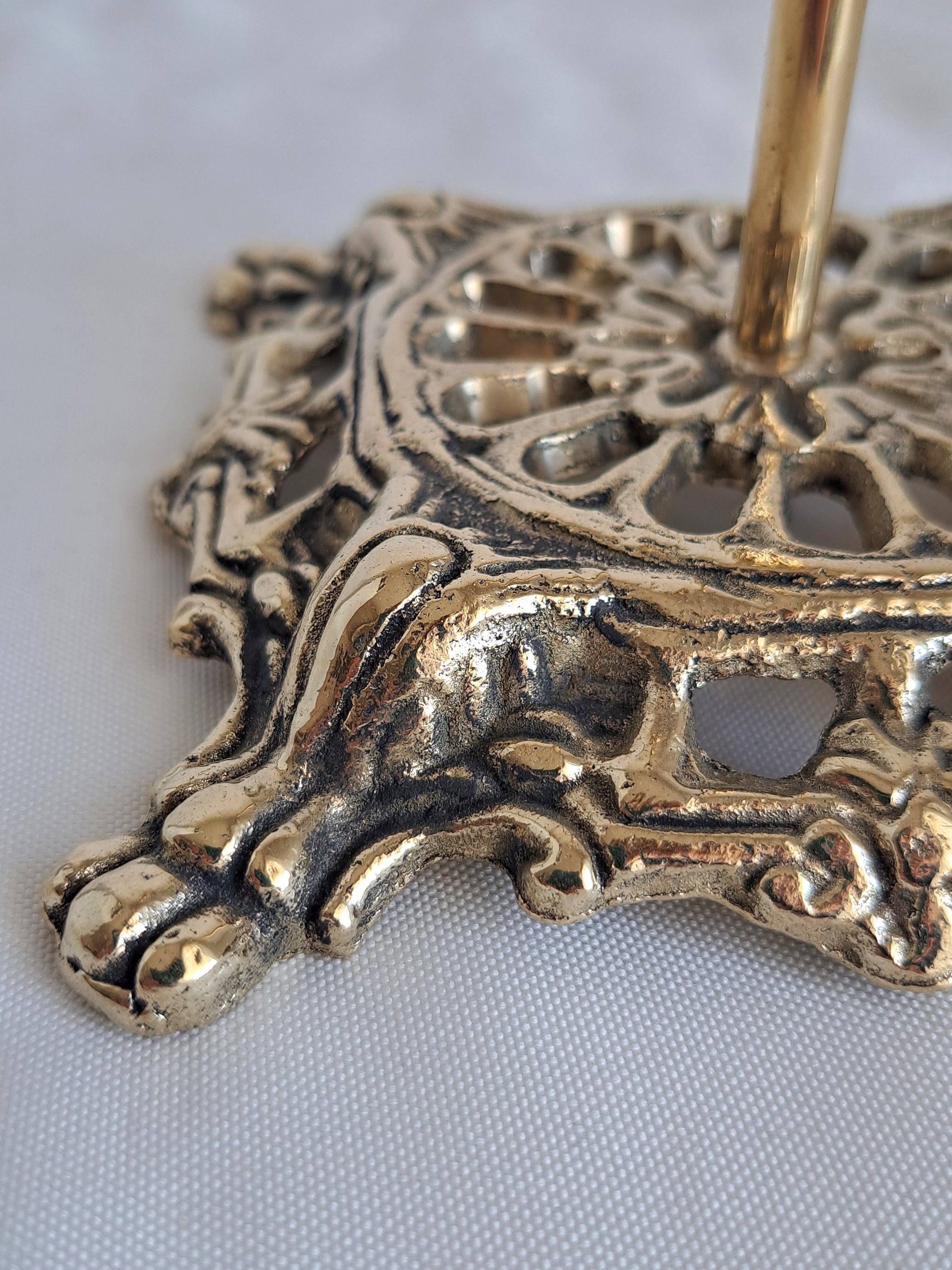 Decorative gold metal stand with intricate patterns on a white background