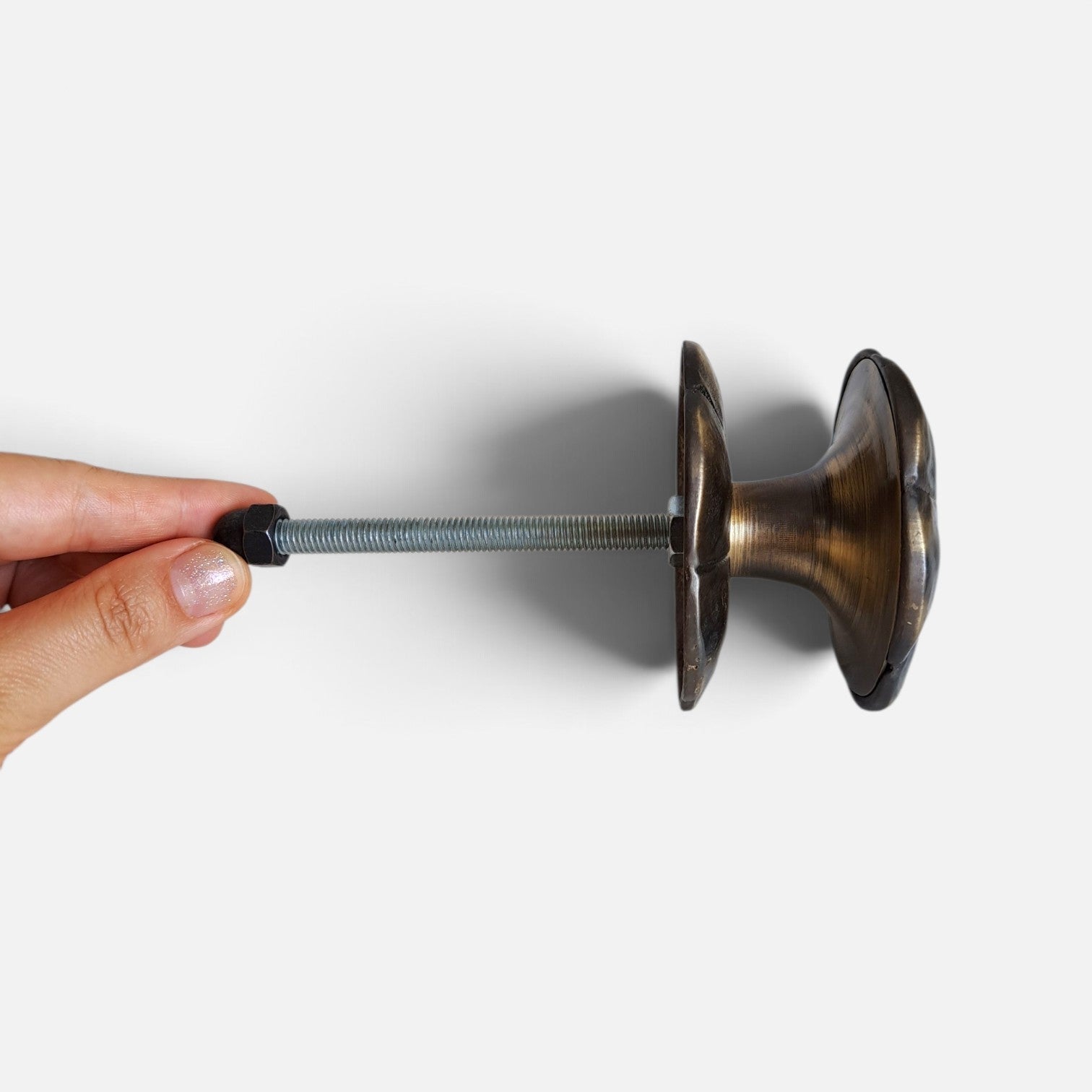 Handmade flower shaped brass door pull shown in a hand for scale