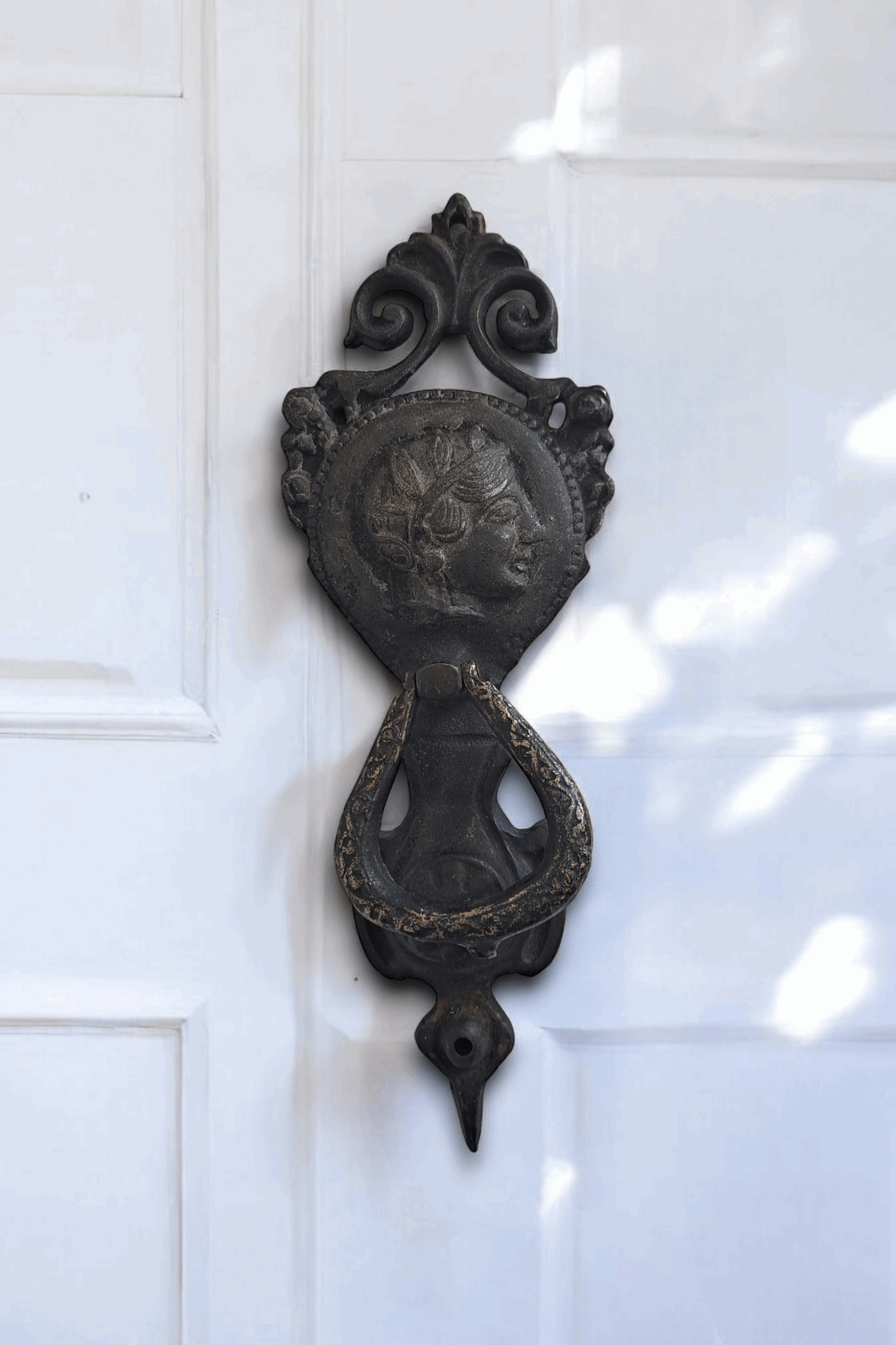 Brass door knocker is on white door