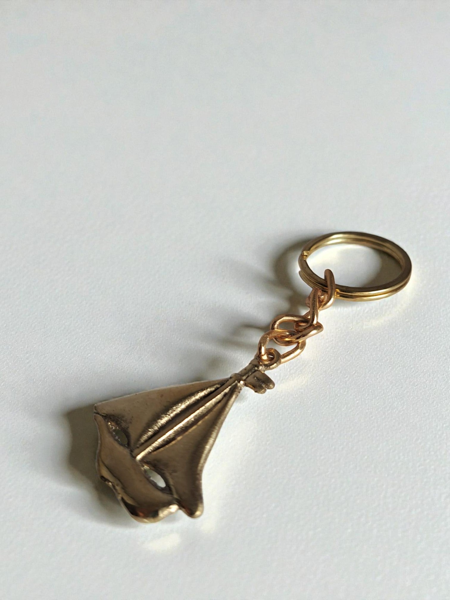 Gold sailboat keychain on a light gray background