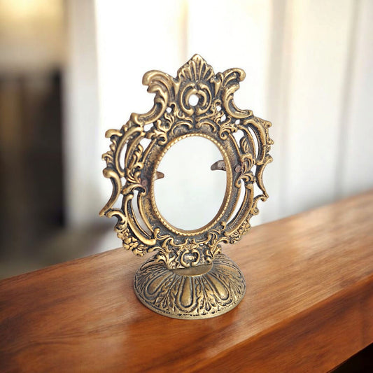 Decorative gold mirror on a wooden surface with a blurred background
