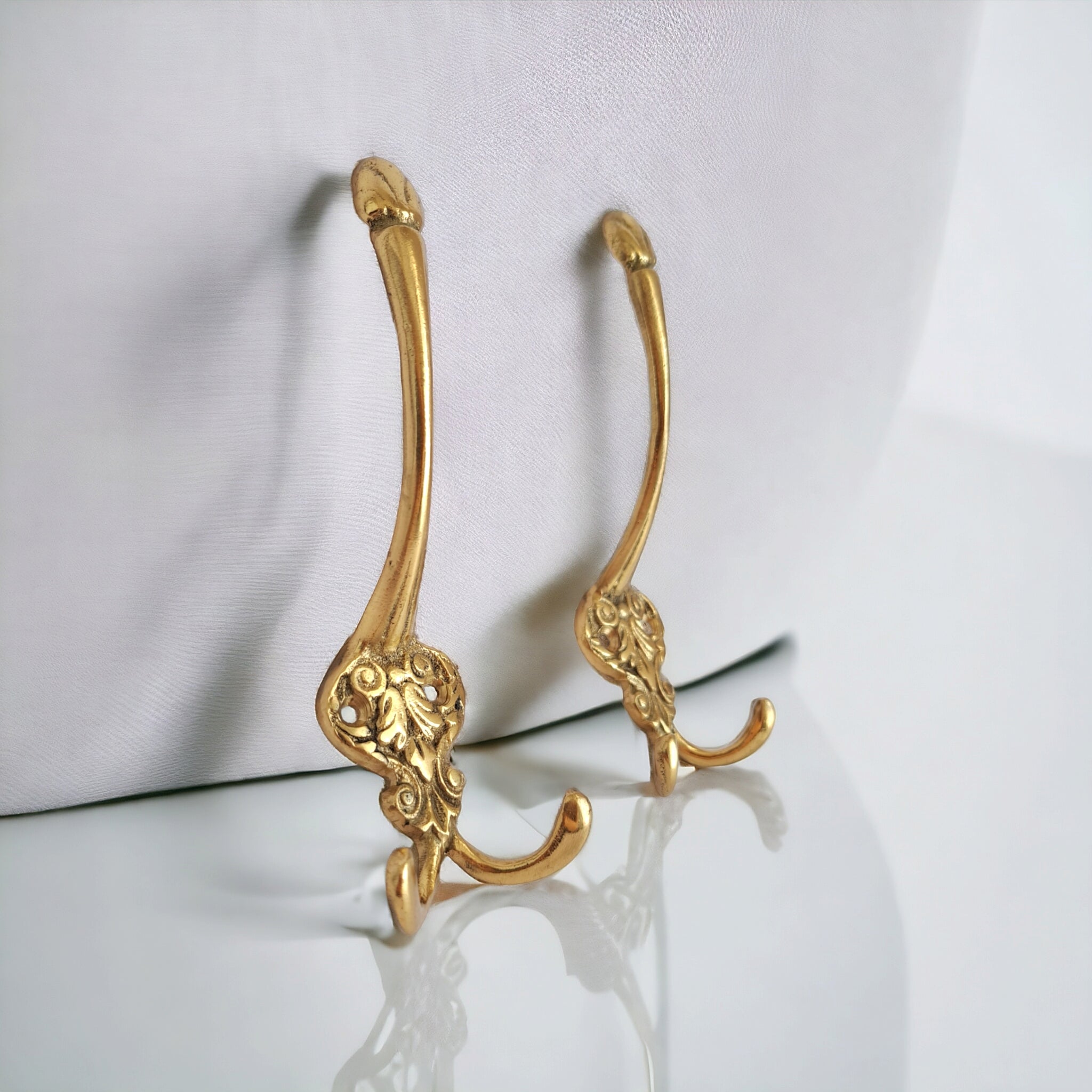 Pair of gold decorative hooks on a white background