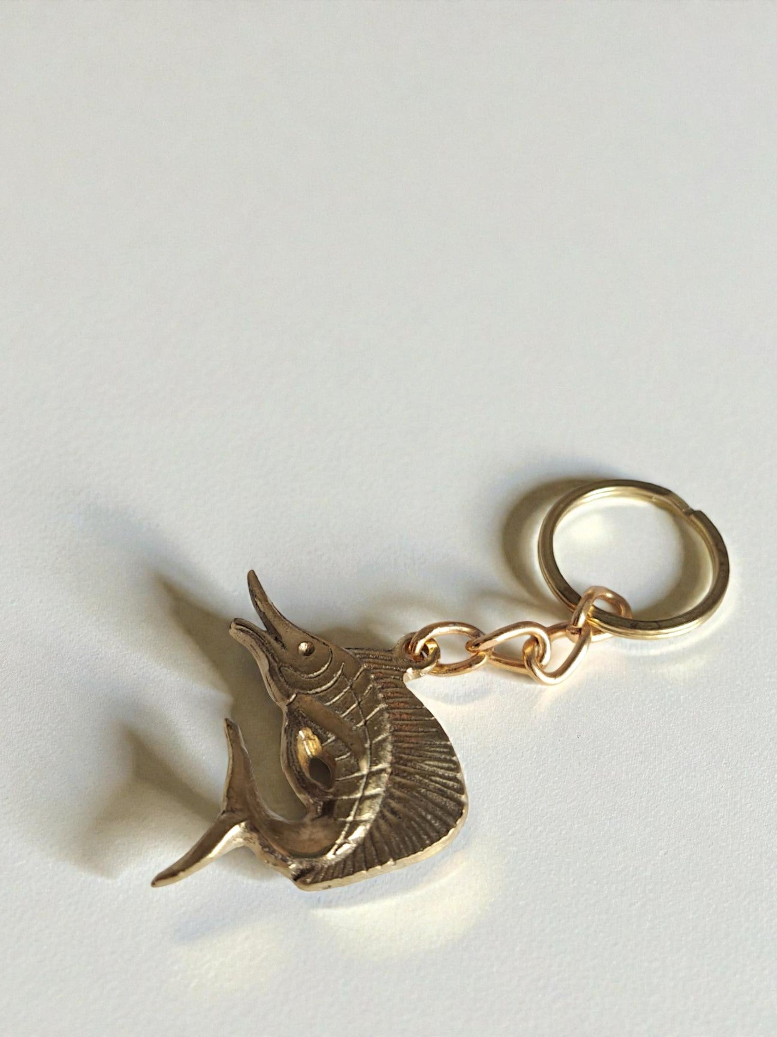 Gold fish-shaped keychain on a light gray background