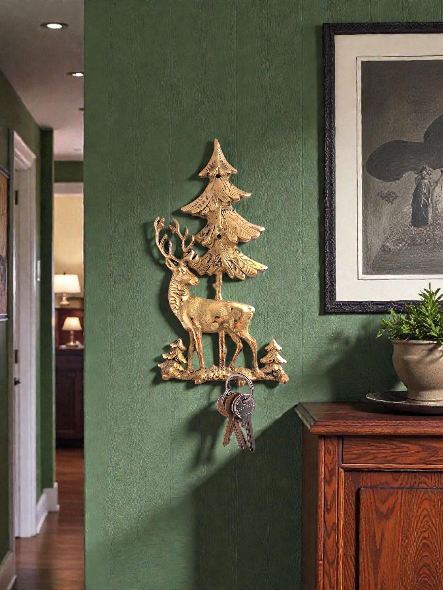 Decorative wall piece with deer and trees on a green wall next to a wooden cabinet.