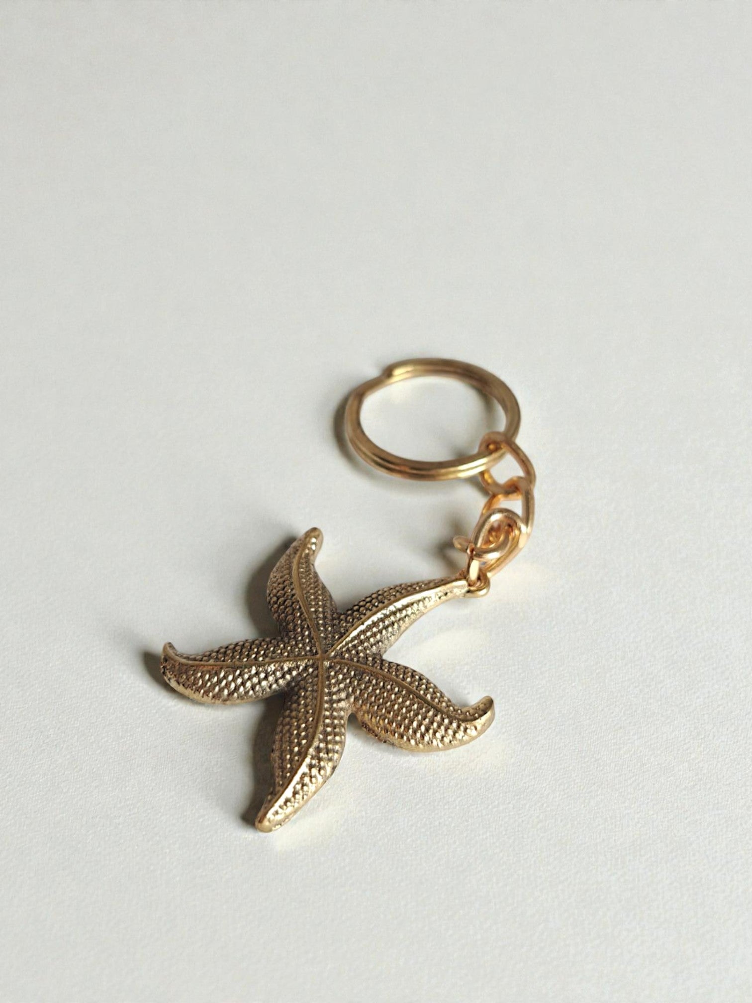Gold starfish keychain on a light gray background