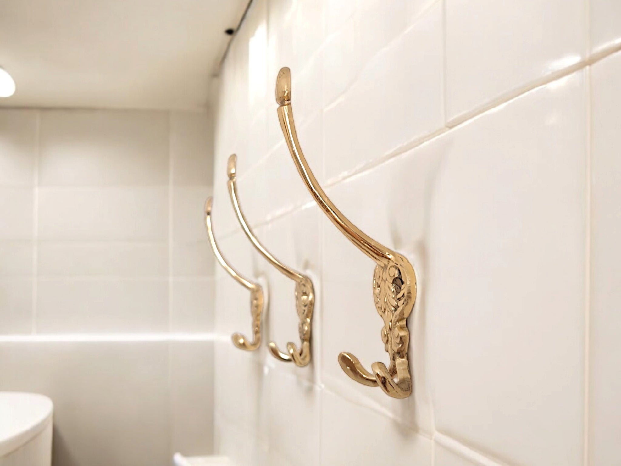 Gold decorative hooks on a tiled bathroom wall