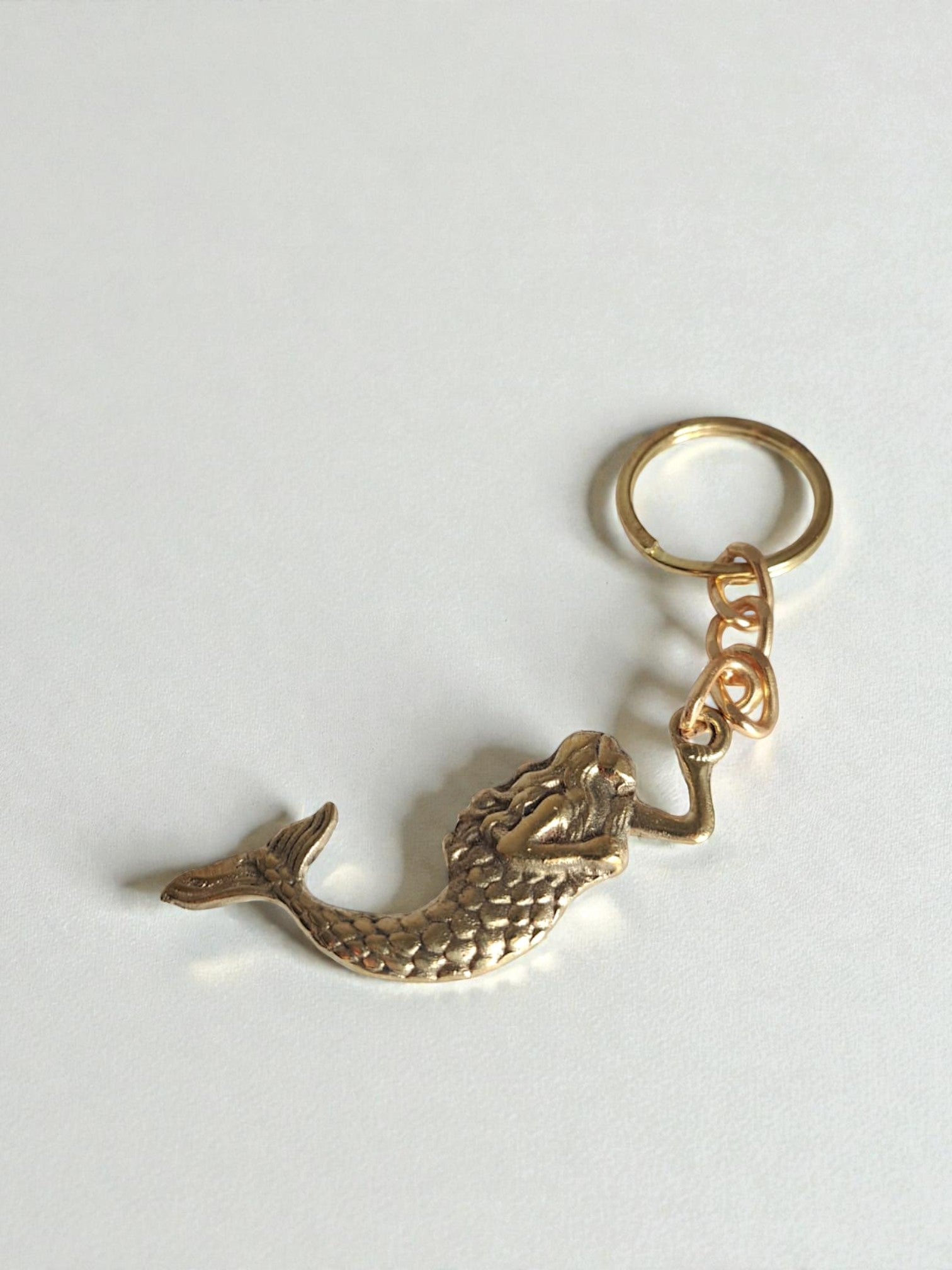 Gold mermaid tail keychain on a white background