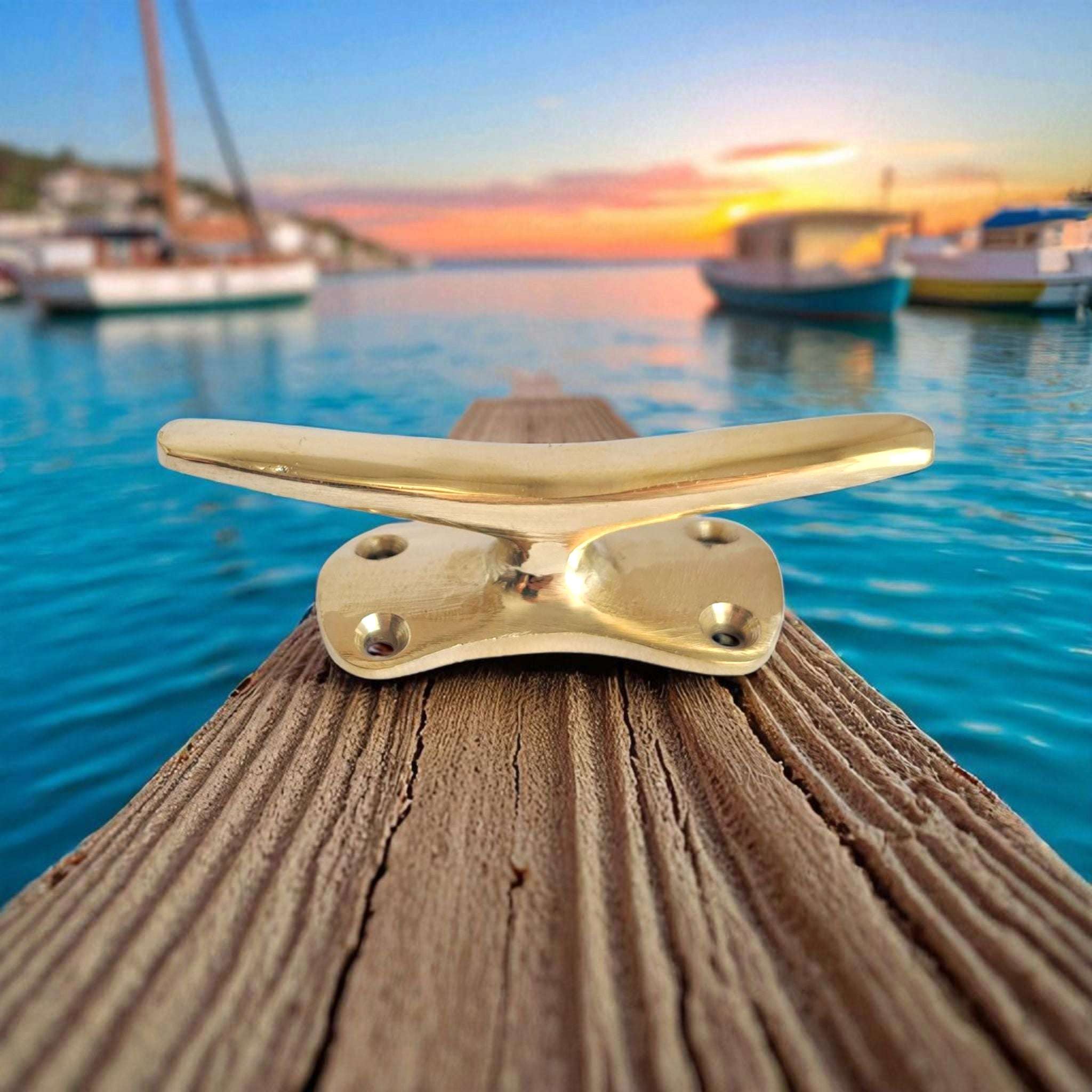 Small brass boat cleat on wooden surface with harbor scene, marine wall decor