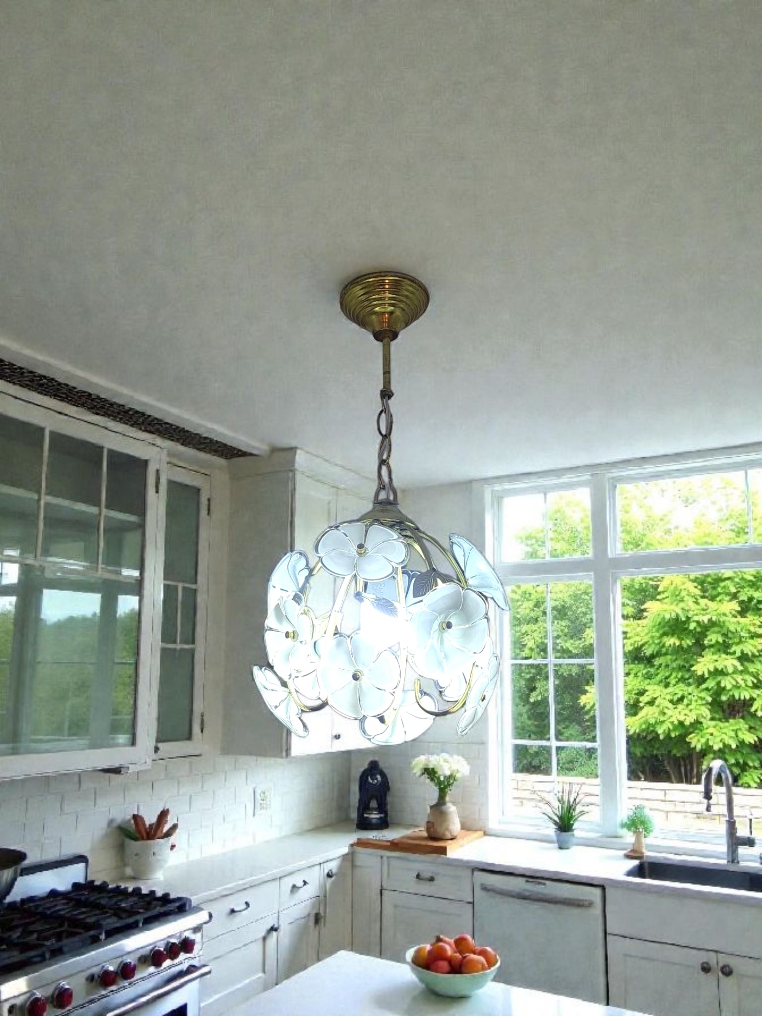 Kitchen with a decorative pendant light, white cabinets, and a window view of greenery.