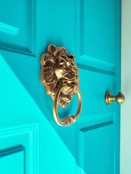 Gold lion-shaped door knocker on a turquoise door