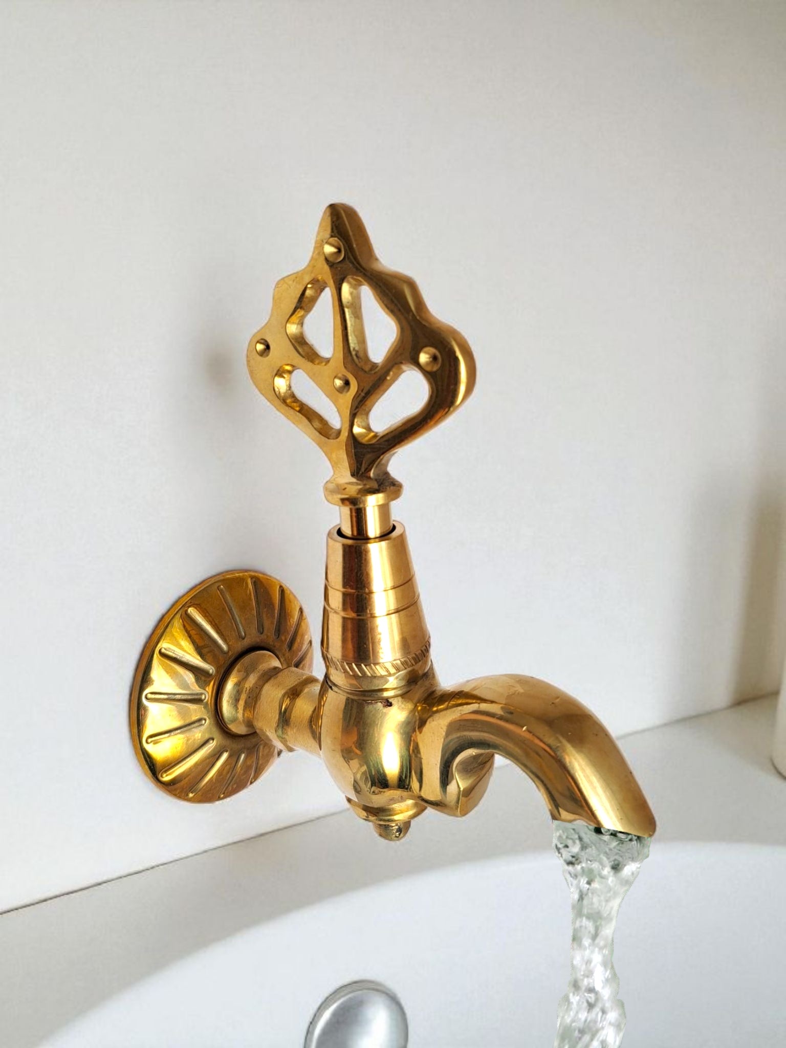 Gold faucet with water flowing on a white background