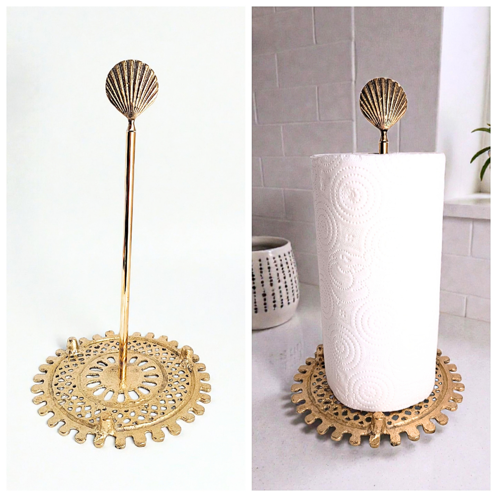 Decorative gold paper towel holder with shell design on a white surface.