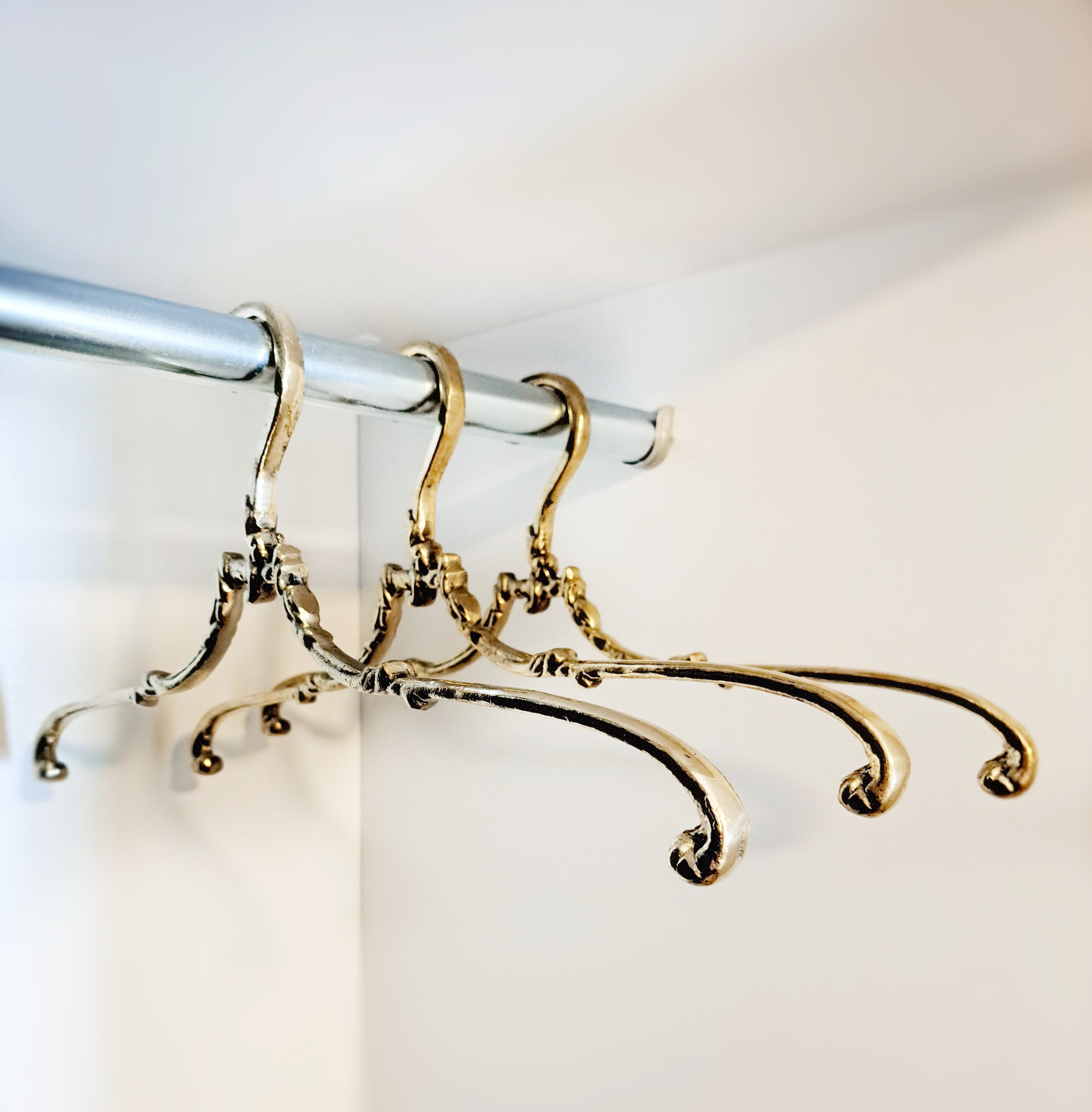 Decorative gold hangers on a silver rod against a white background