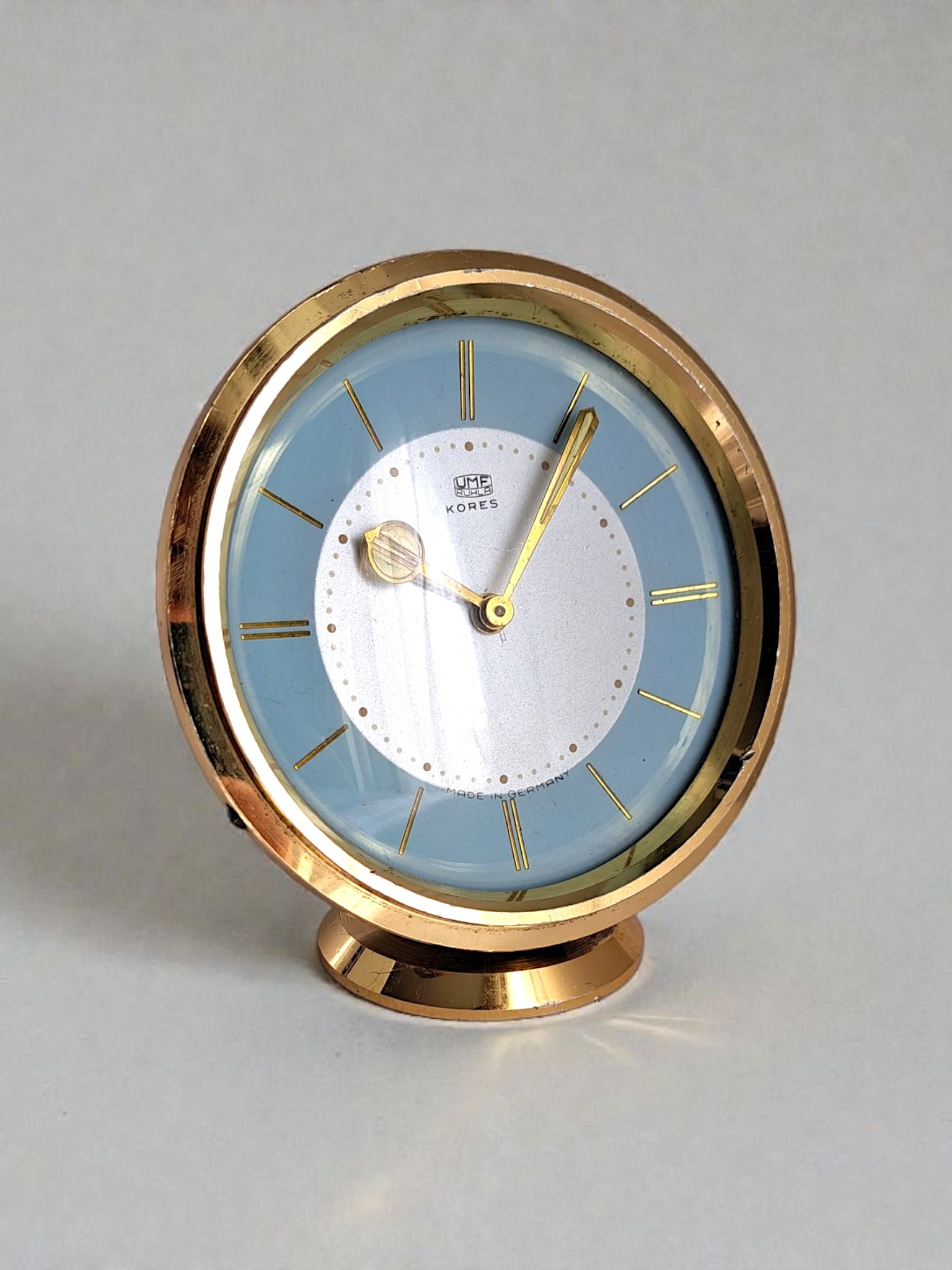 Decorative clock with gold frame and blue face on a gray background