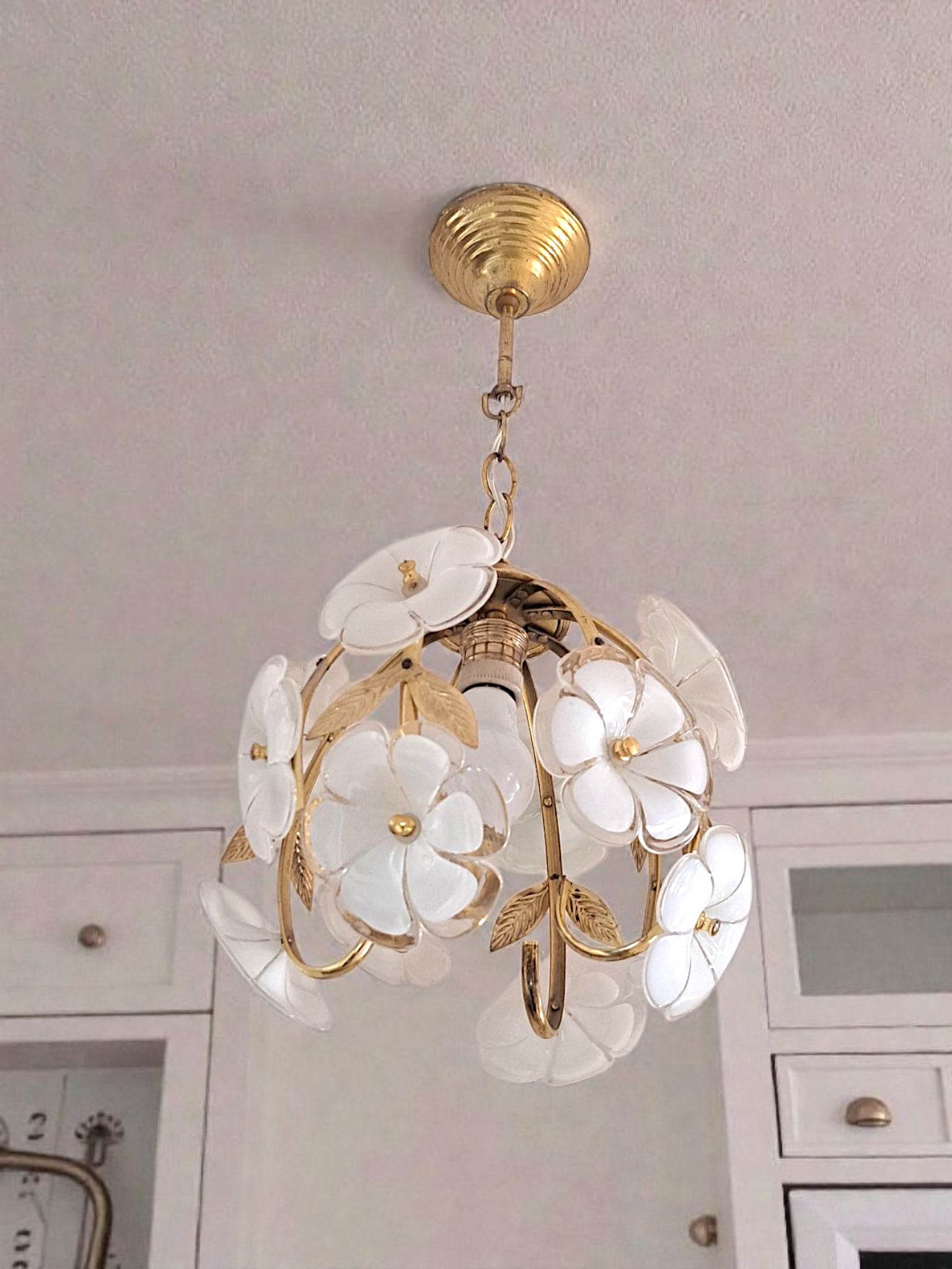 Floral chandelier with white flowers and gold accents hanging from a ceiling.